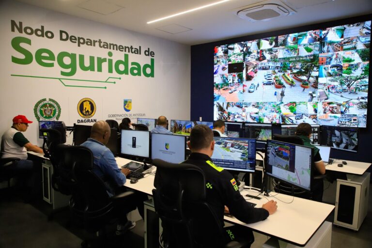 Uniformados en azul frente a pantallas LED, analizan mapas y cámaras en centro de control.